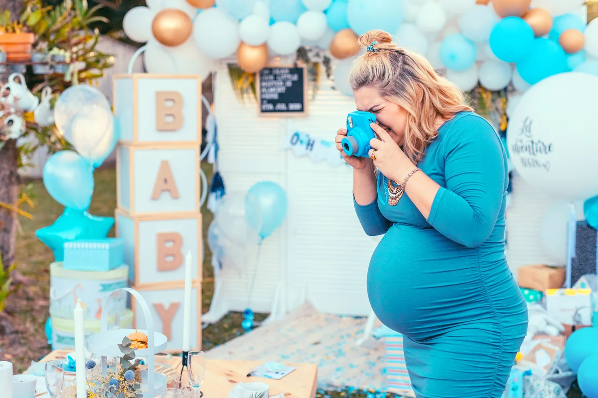 Pregnant woman taking photos of a decorated table for baby shower