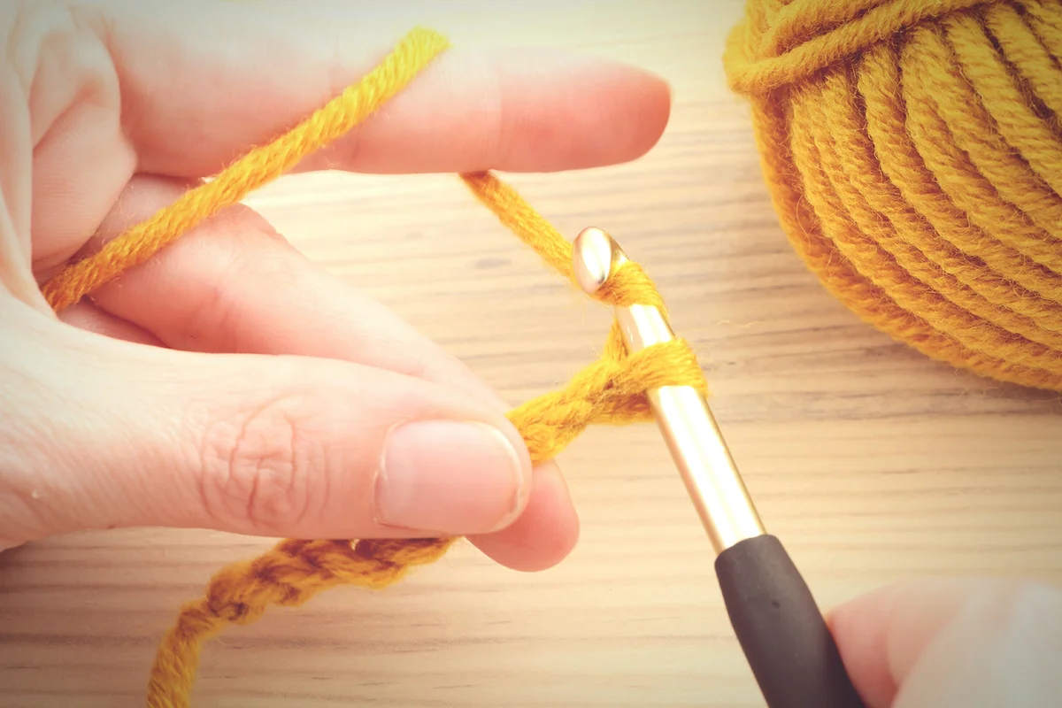 Hands Crocheting Wool Over Table