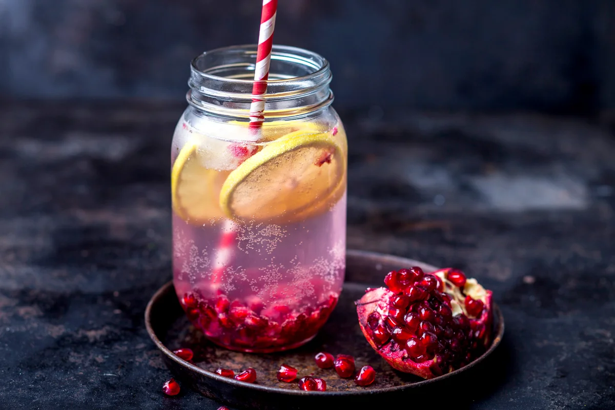 Fruit infused water with lemon slices, crushed pomegranate seeds and sparkling water
