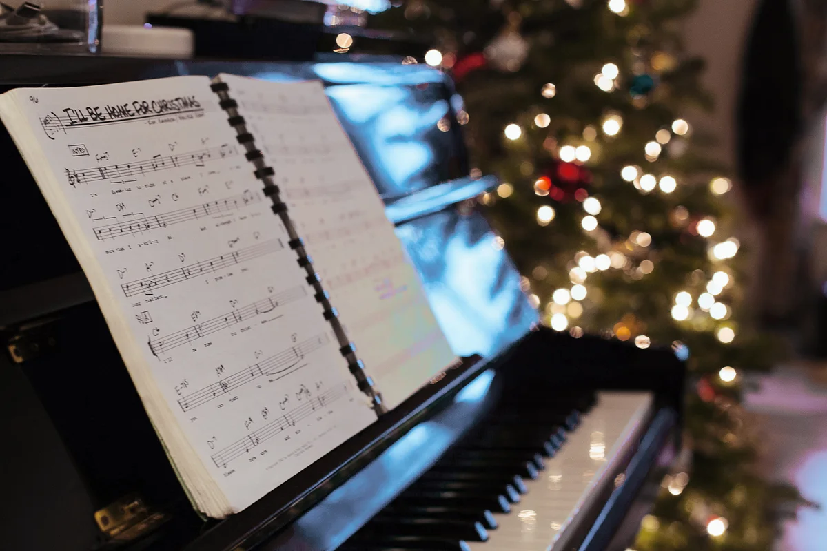 Sheet music on piano, Christmas tree in background