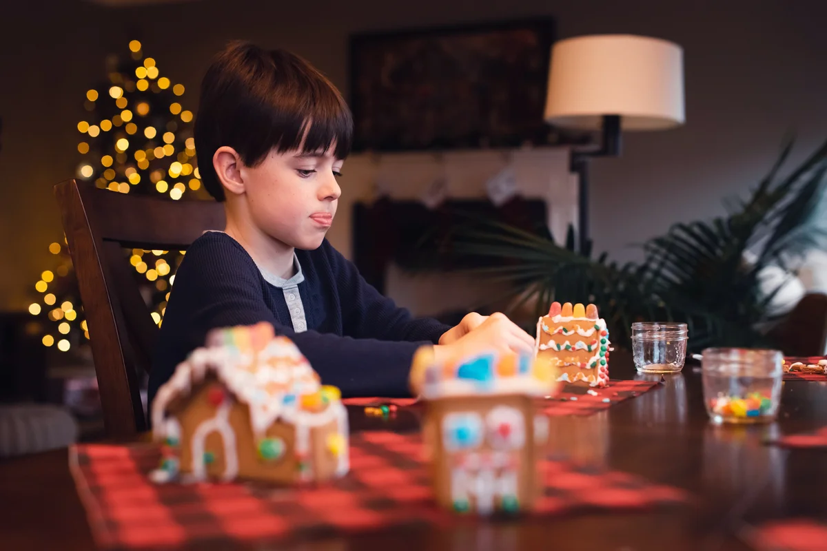 Young boy decorating gingerbread house