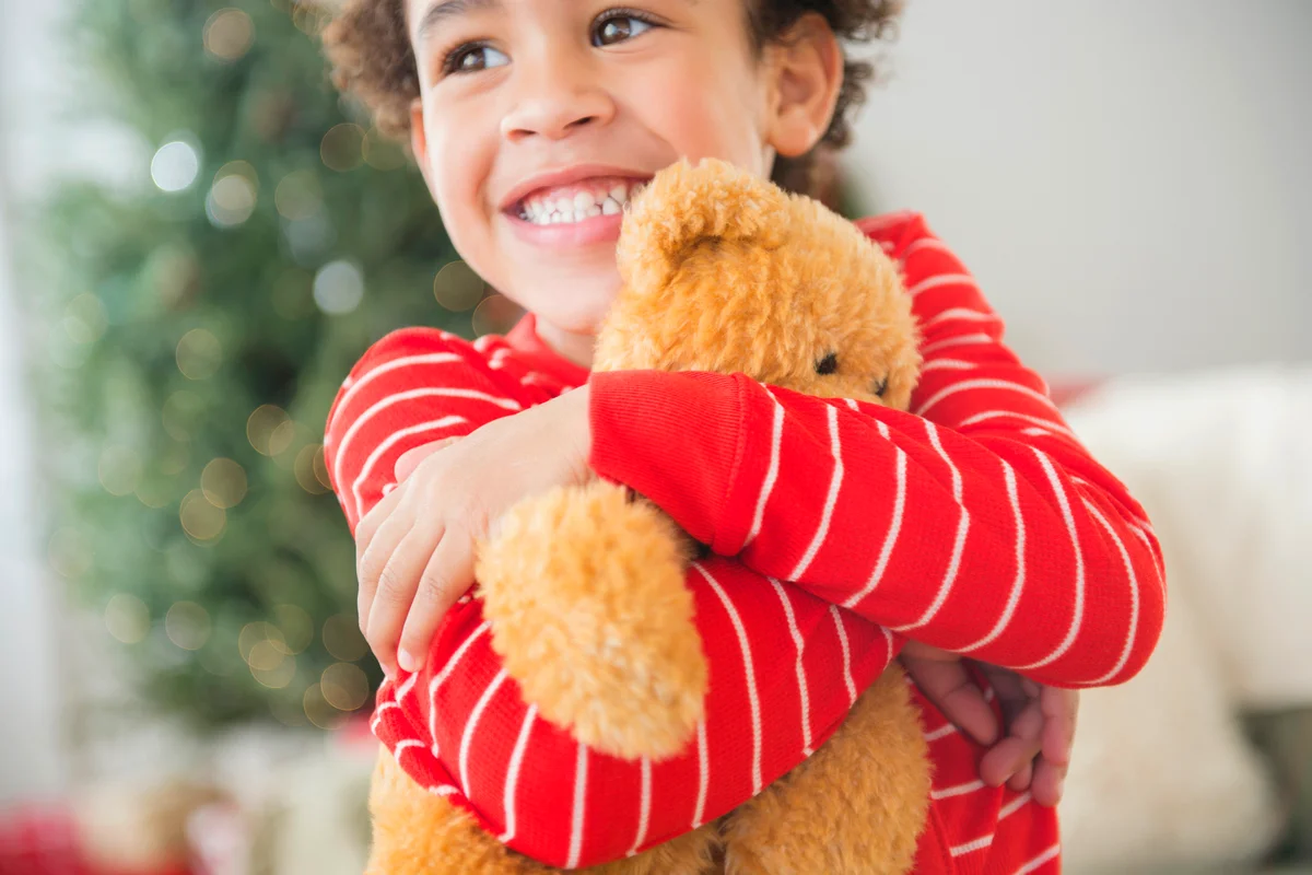 Girl hugging teddy bear at Christmas