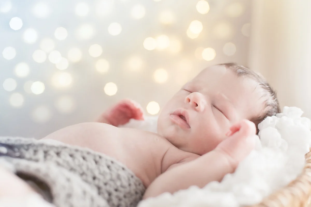 Newborn in front of a background with sparkling lights