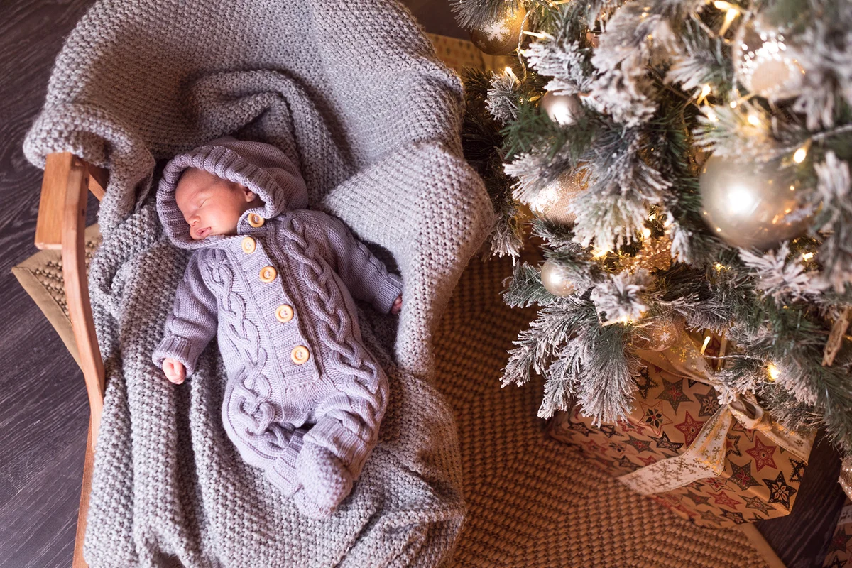 Baby boy sleeping under the Christmas tree