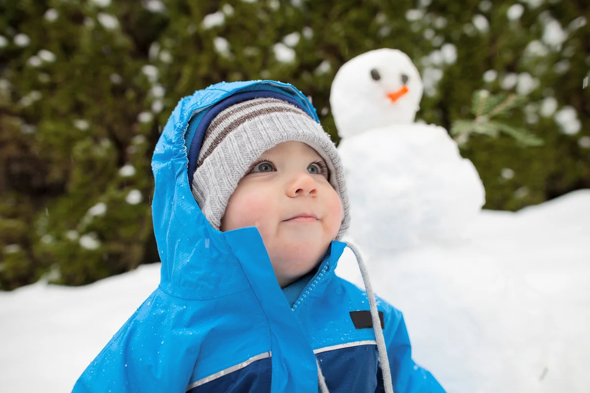baby boy outdoors with snowman in background
