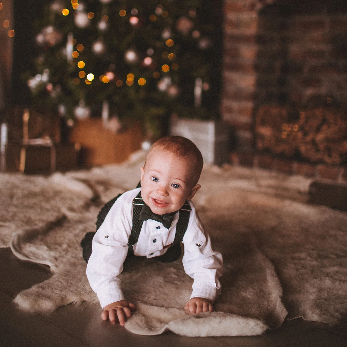 Baby Boy Crawling On Floor Against Christmas Tree At Home