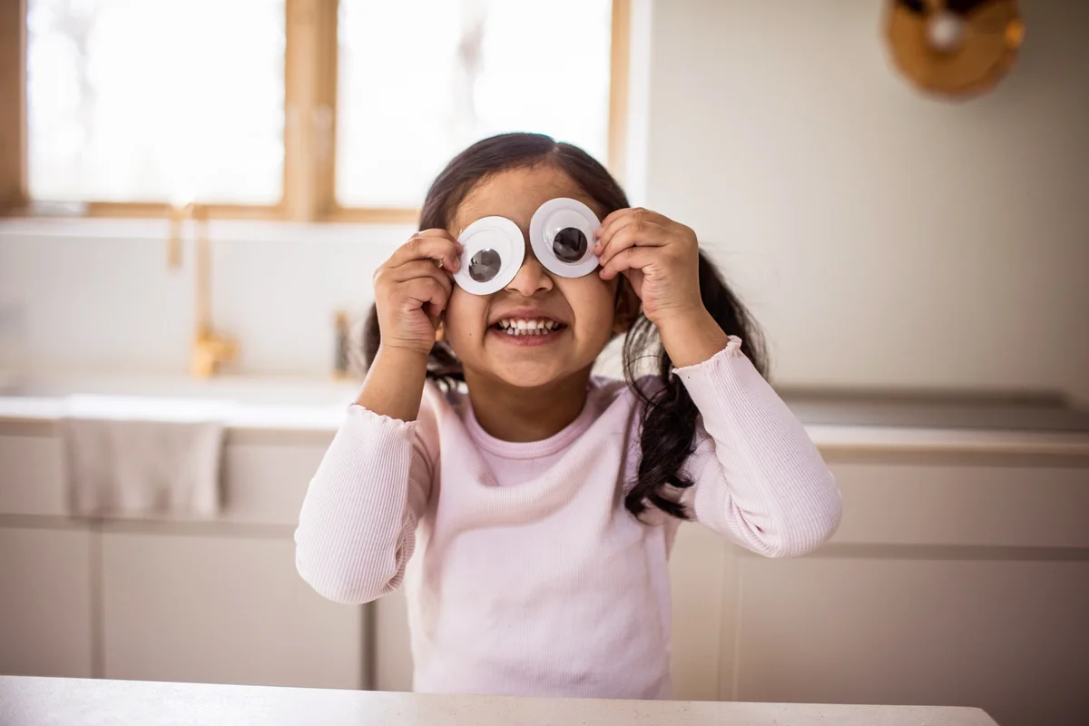 Young girl playing with silly googly eyes at home