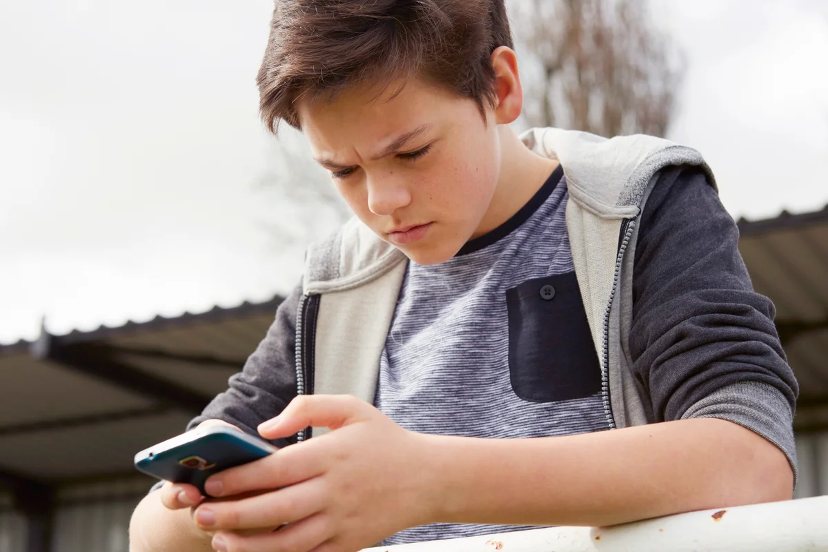 Confused teenage boy looking at smartphone