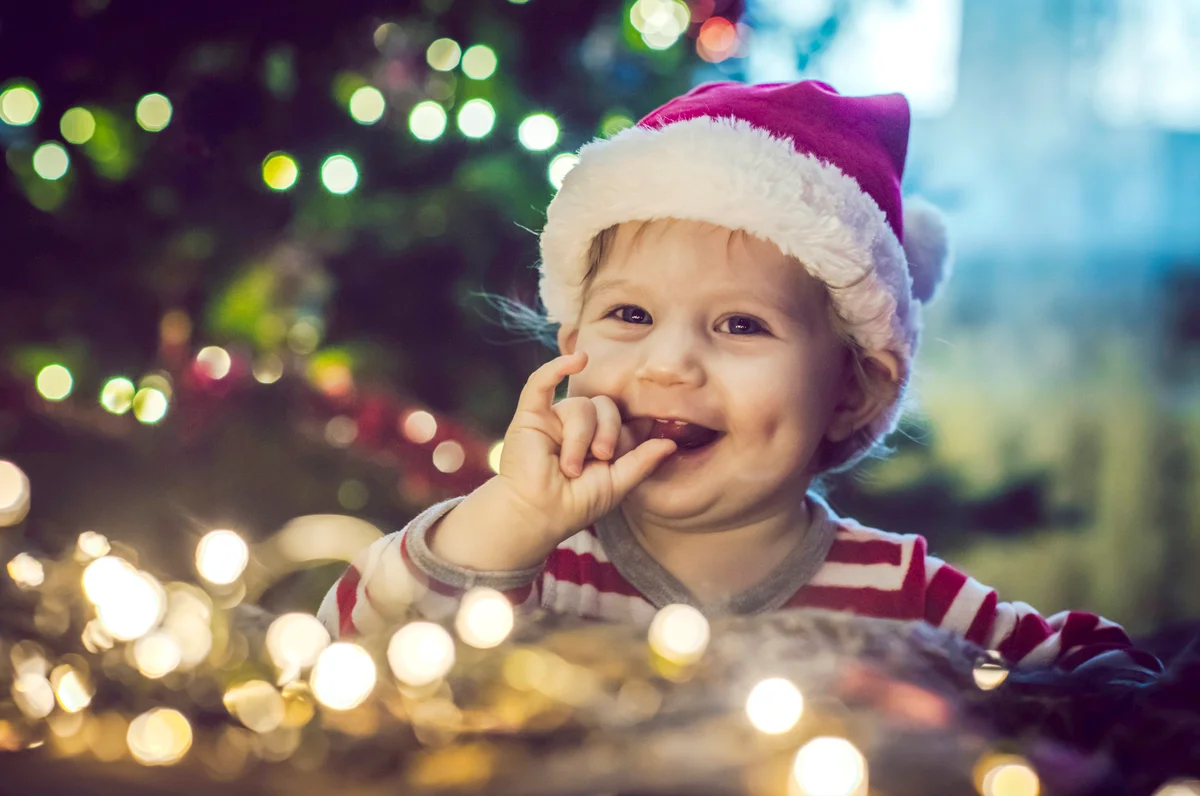 Child playing with lights near Christmas tree