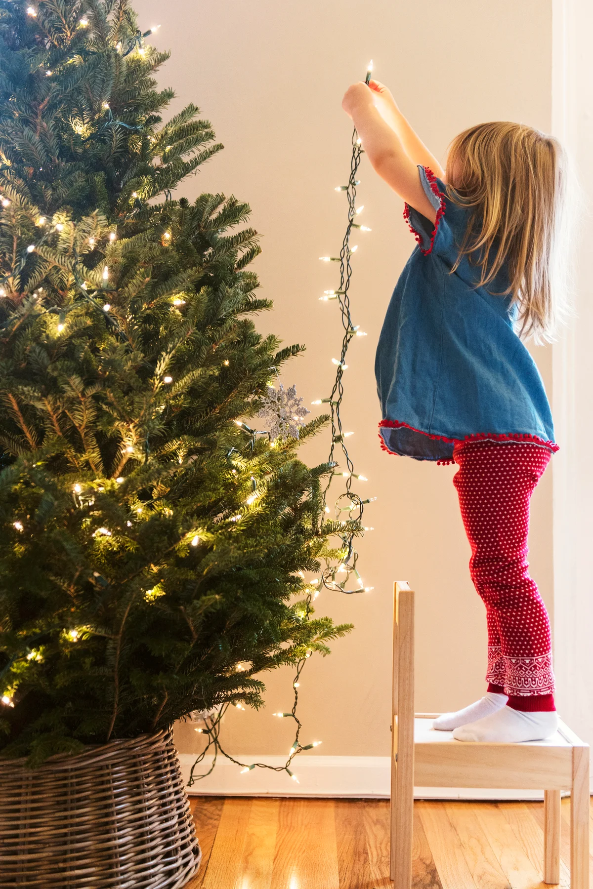 Girl hanging lights on Christmas tree