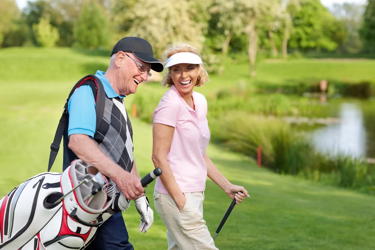 Cheerful mature couple walking on a golf course