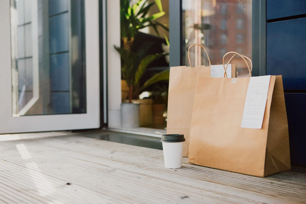Takeaway meal packed in brown paper bag delivered to the front door