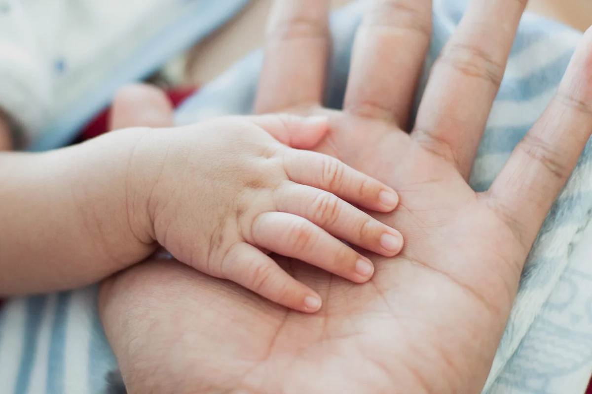 shot of father and baby's hand