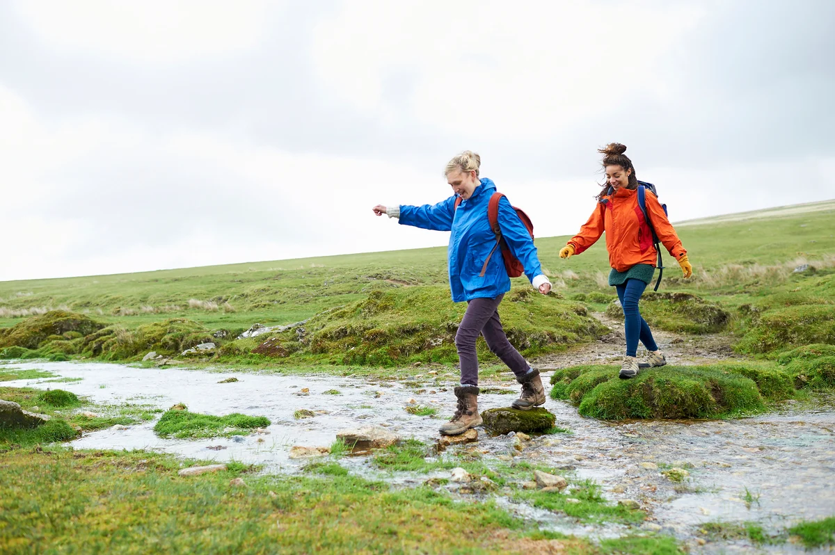 Two hikers crossing stream in countryside