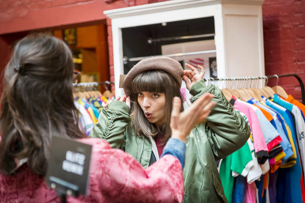 Two young women trying on beret at vintage clothes stall