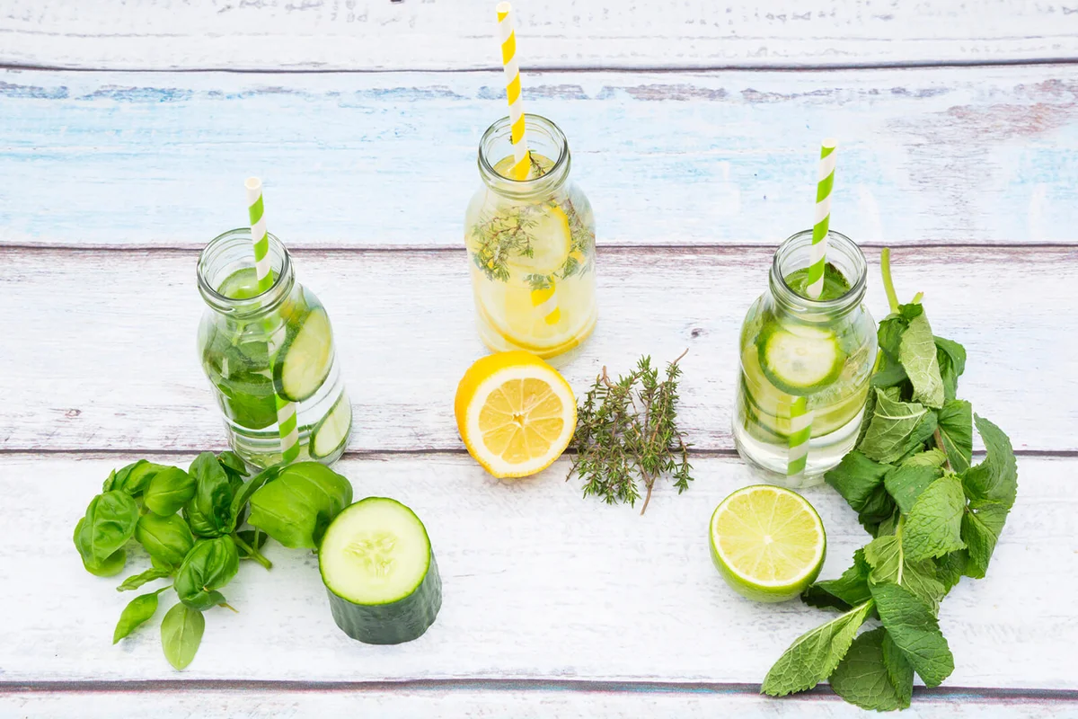 Three glass bottles of table water flavored with different fruits and herbs
