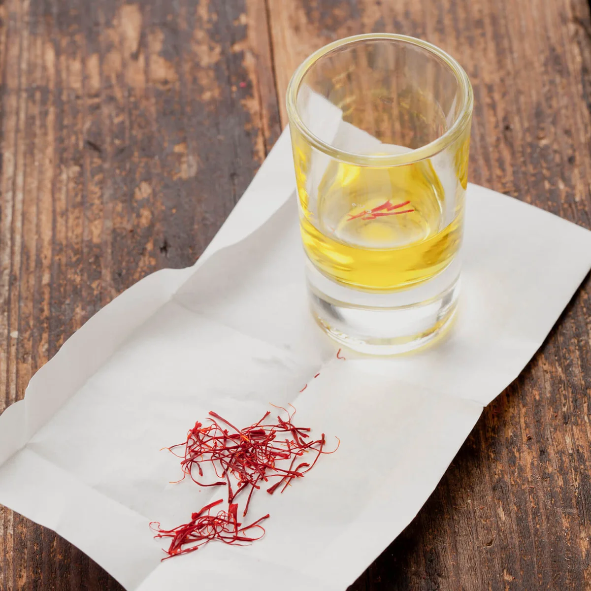 Saffron threads and glass of water on paper
