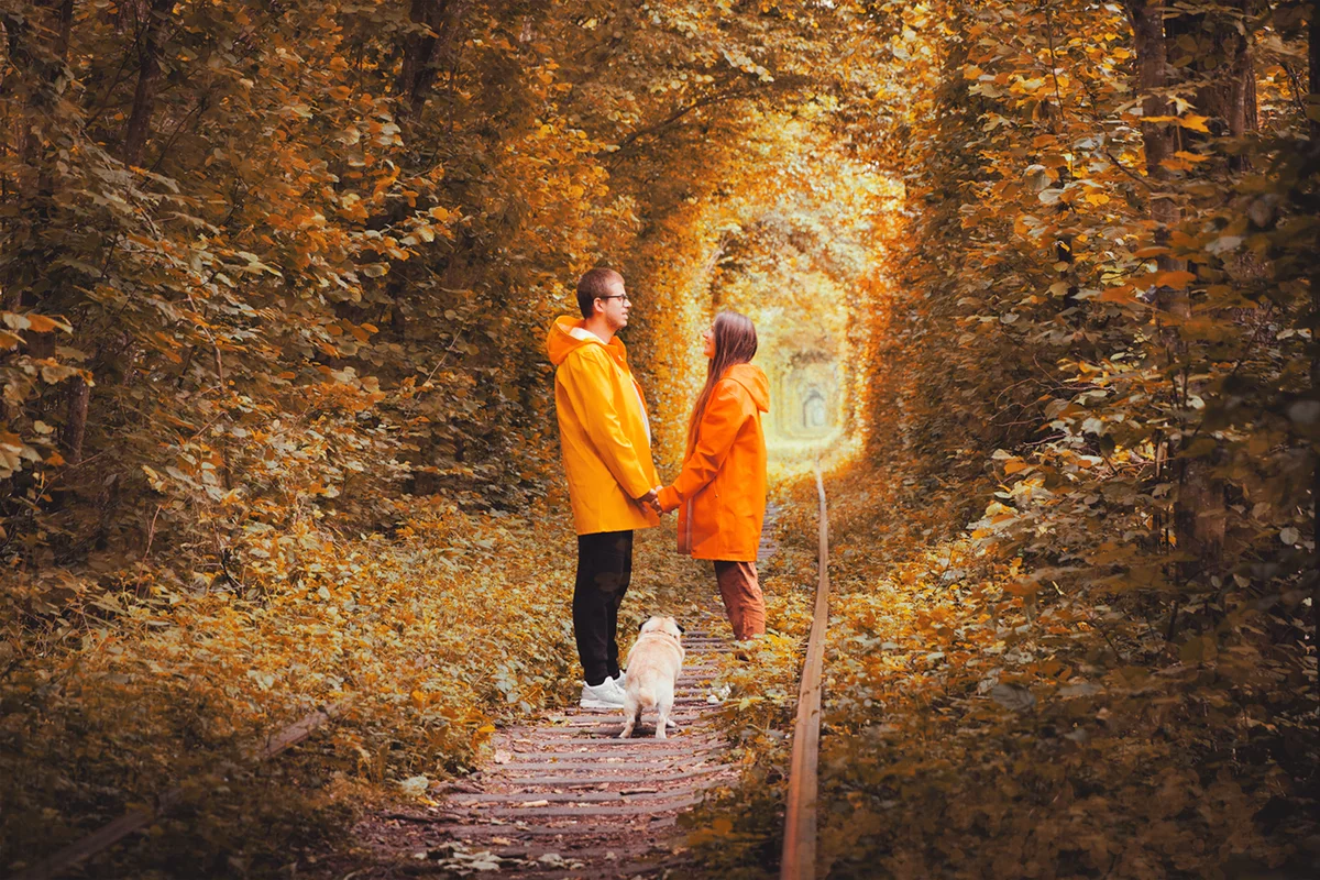 Happy young couple in raincoats with dog
