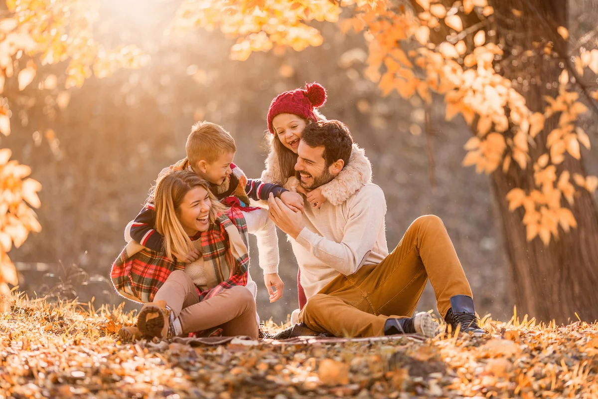 Playful family having fun in autumn day at the park