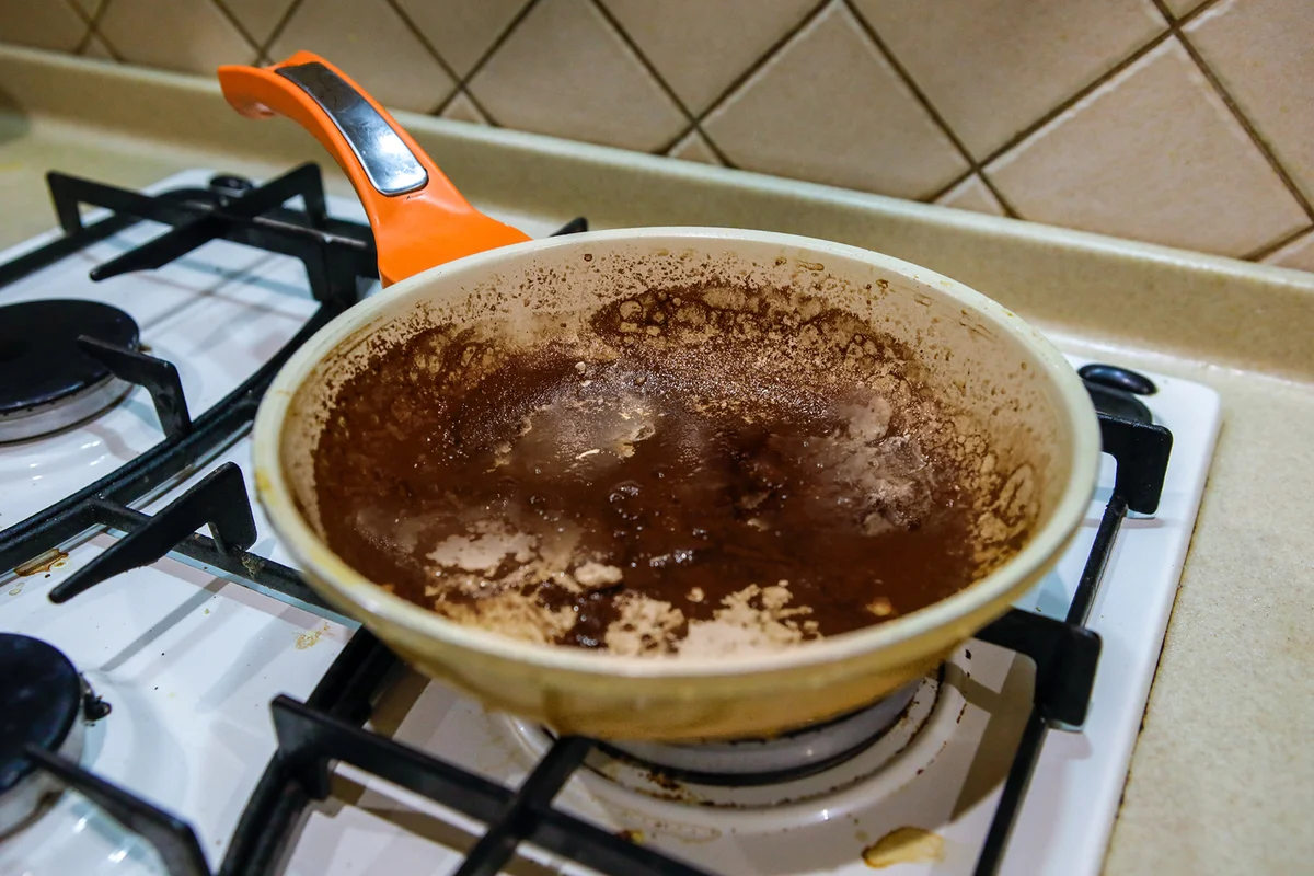 On the stove is a dirty, burnt, unwashed pan
