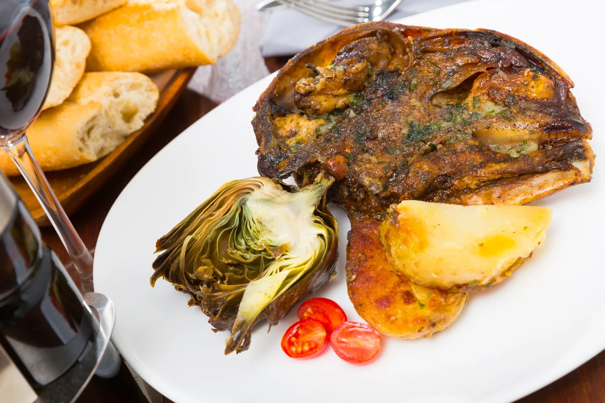 Lamb head with artichoke, tomatoes and potatoes