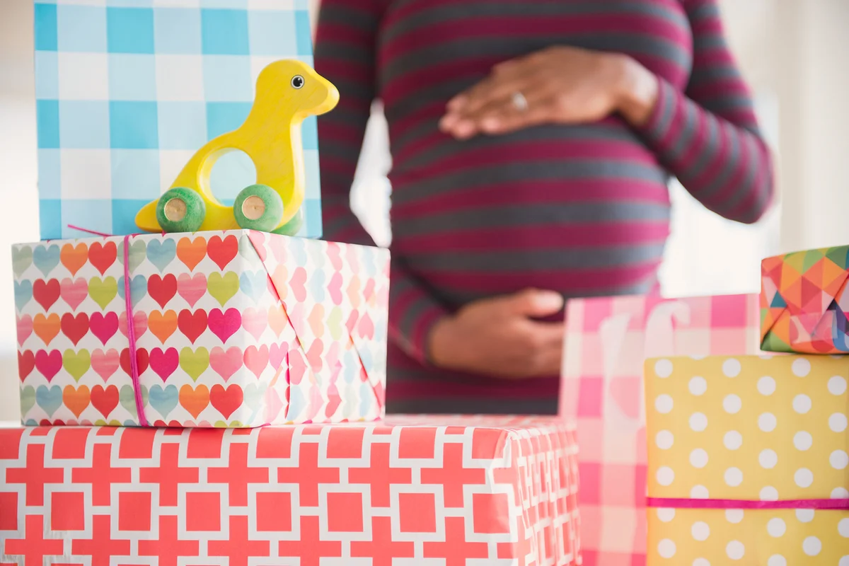 pregnant woman admiring gifts at baby shower