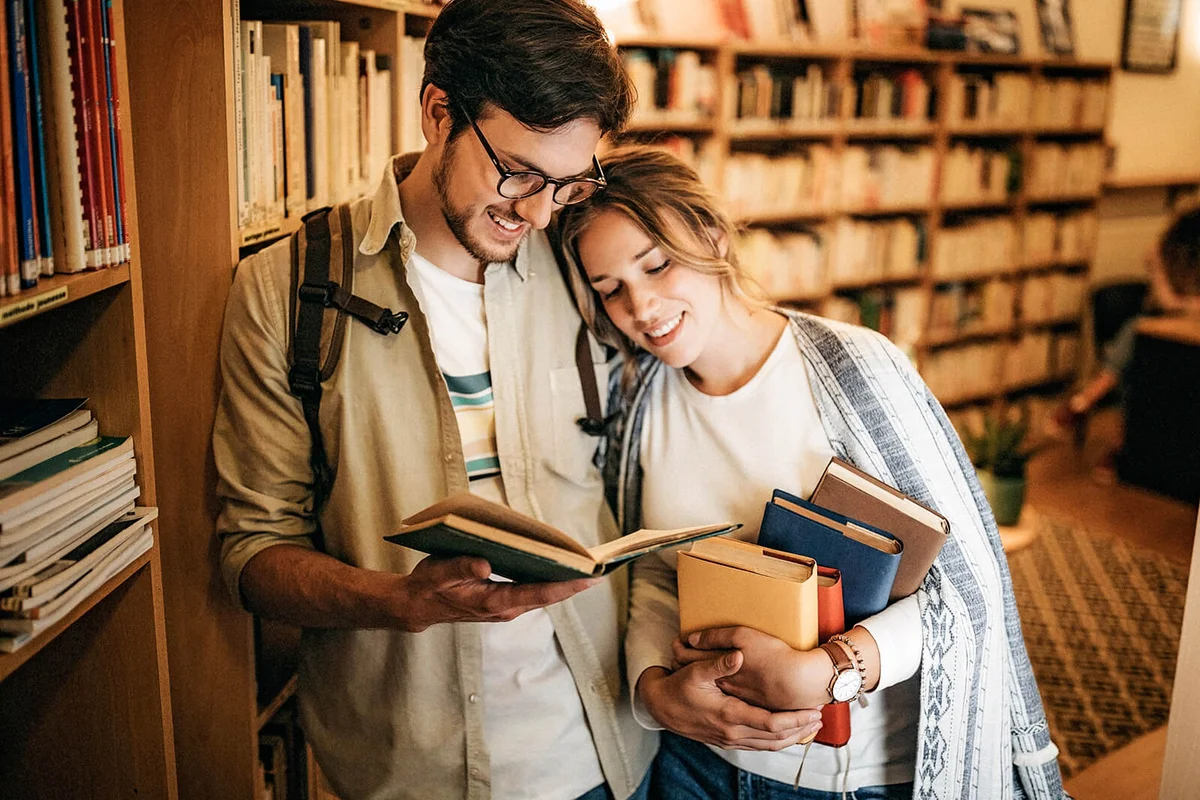 Couple looking for good book to read in library