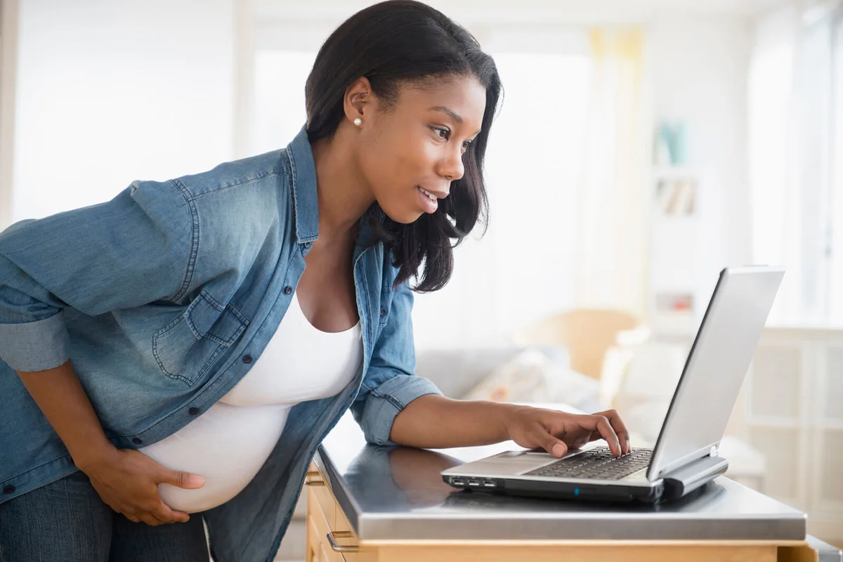 pregnant woman using laptop in kitchen