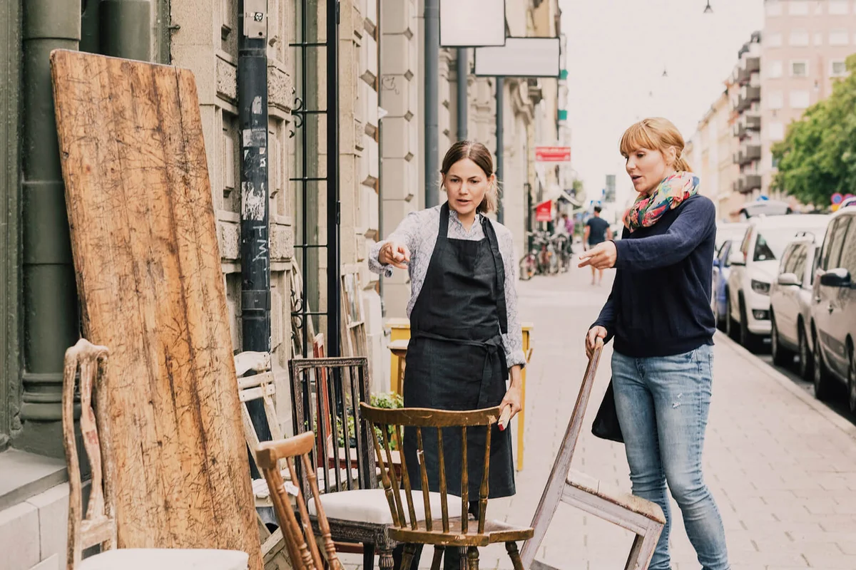 Owner and customer pointing towards chair outside antique shop