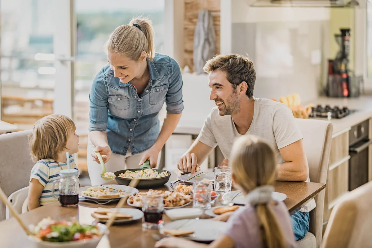woman serving lunch to her family at dining table