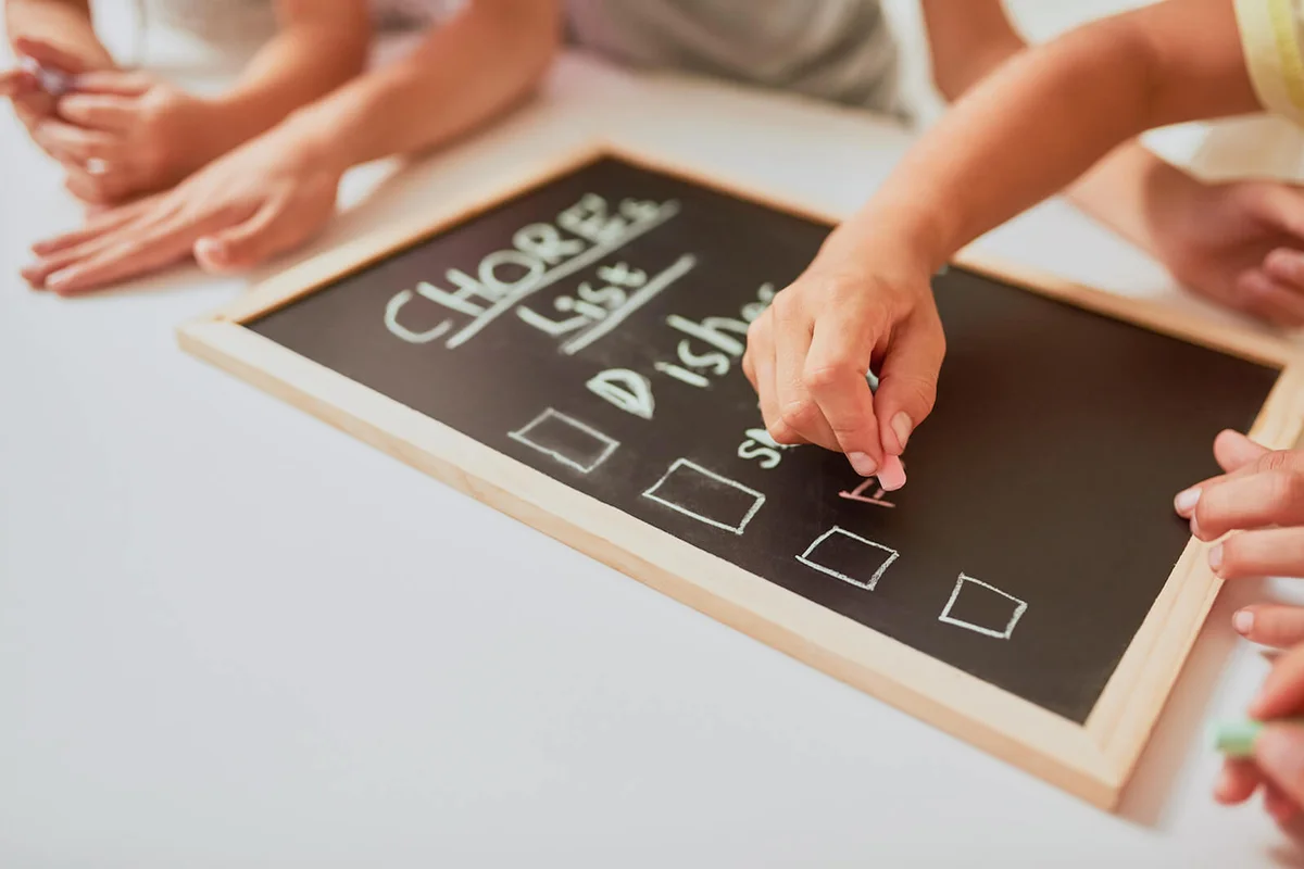kids writing a list of chores on a chalkboard at home