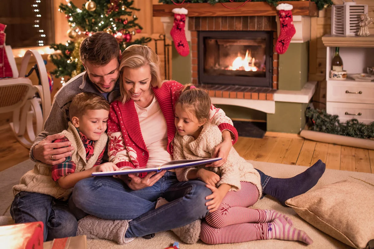 Young happy family reading fairy tales while relaxing at home during Christmas holidays