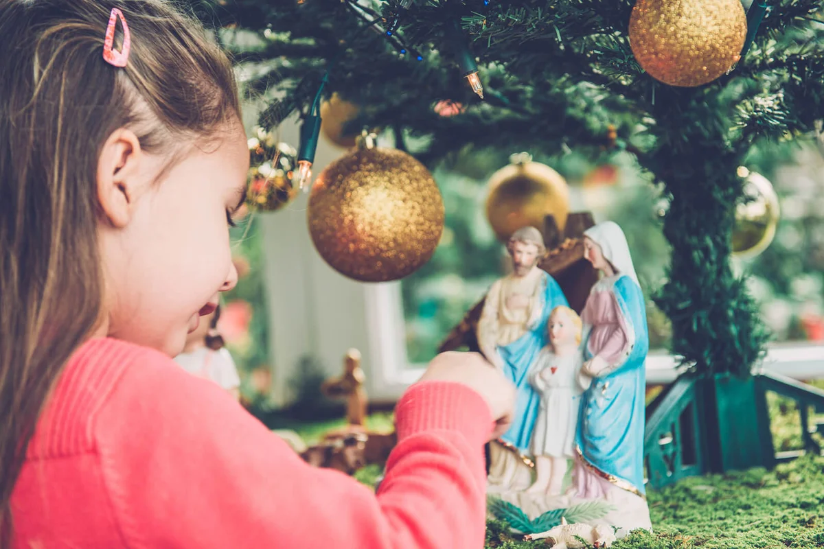 Girl Playing with Figurines at Nativity Scene