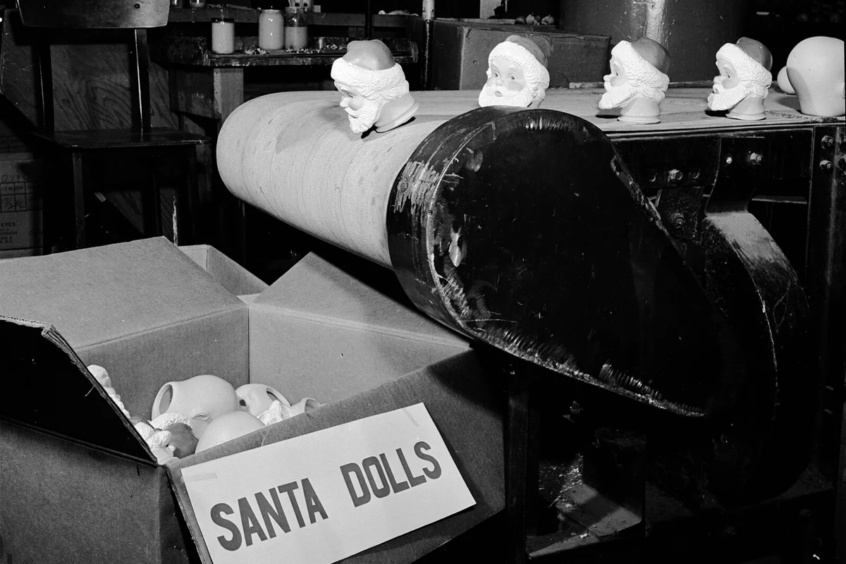 The heads of Santa Claus dolls fall from a conveyor belt ready to be transported to the next department at the Ideal Toy Corporation in Hollis, New York.