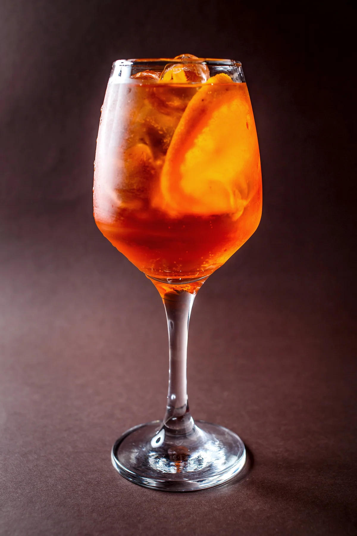 Glass of Spritz with orange on elegant dark brown background