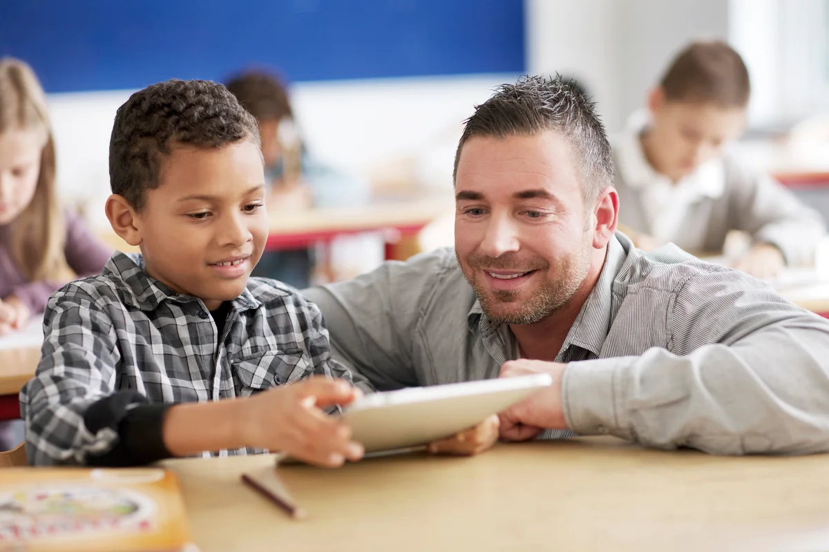 Boy showing teacher schoolwork on tablet computer