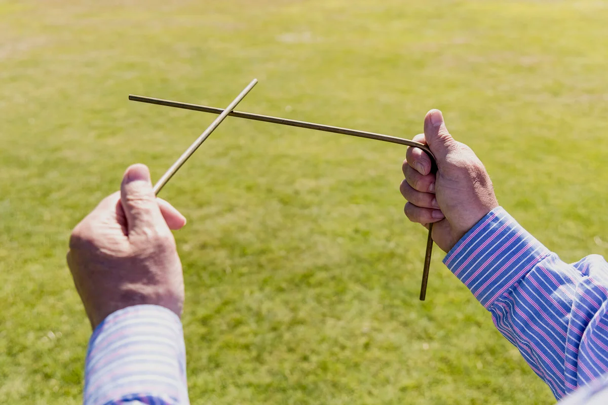 Water diviner demonstrating how dowsing rods are used for water divination at St Michael's Mount tidal island, England, United Kingdom