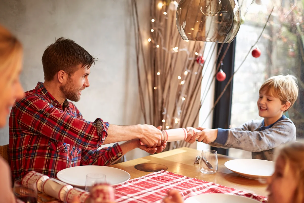 A family around a table at Christmas time, pulling cracker
