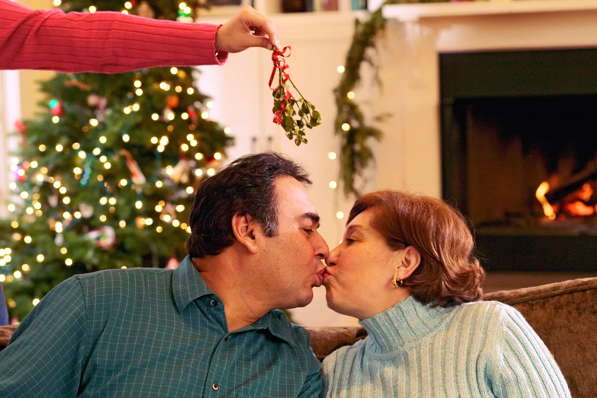 Woman dangling mistletoe in between kissing couple