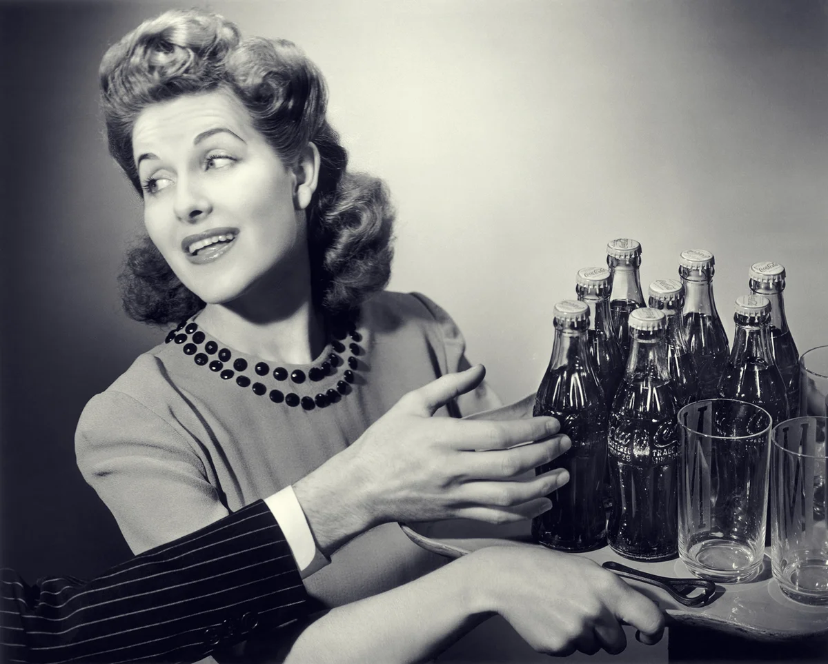 1950s woman carrying tray of drinking glasses & soda
