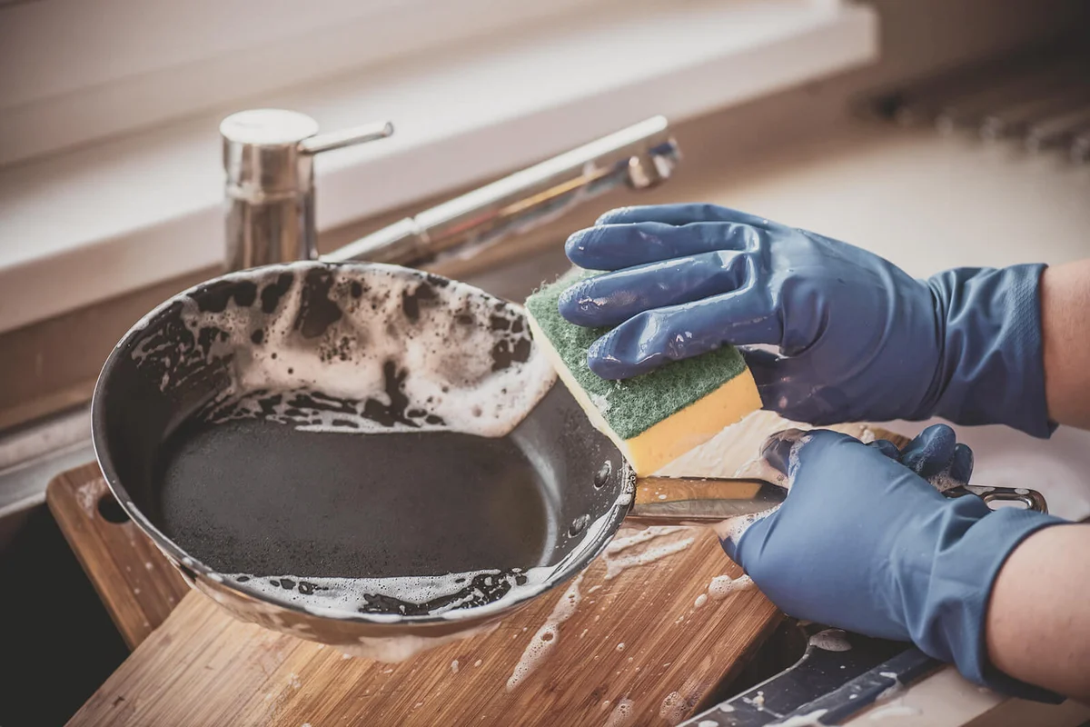 hands in gloves wash dishes with detergents