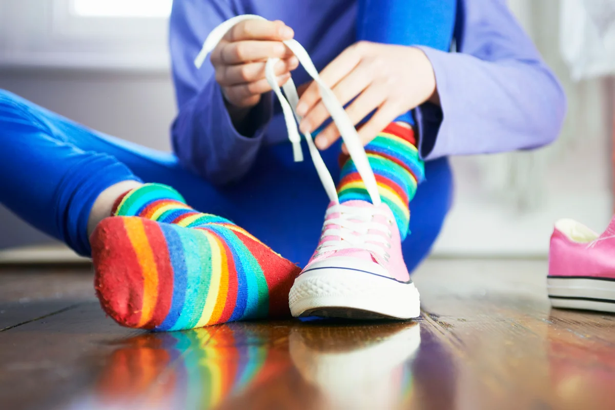 Young child tying shoe laces with colourful socks