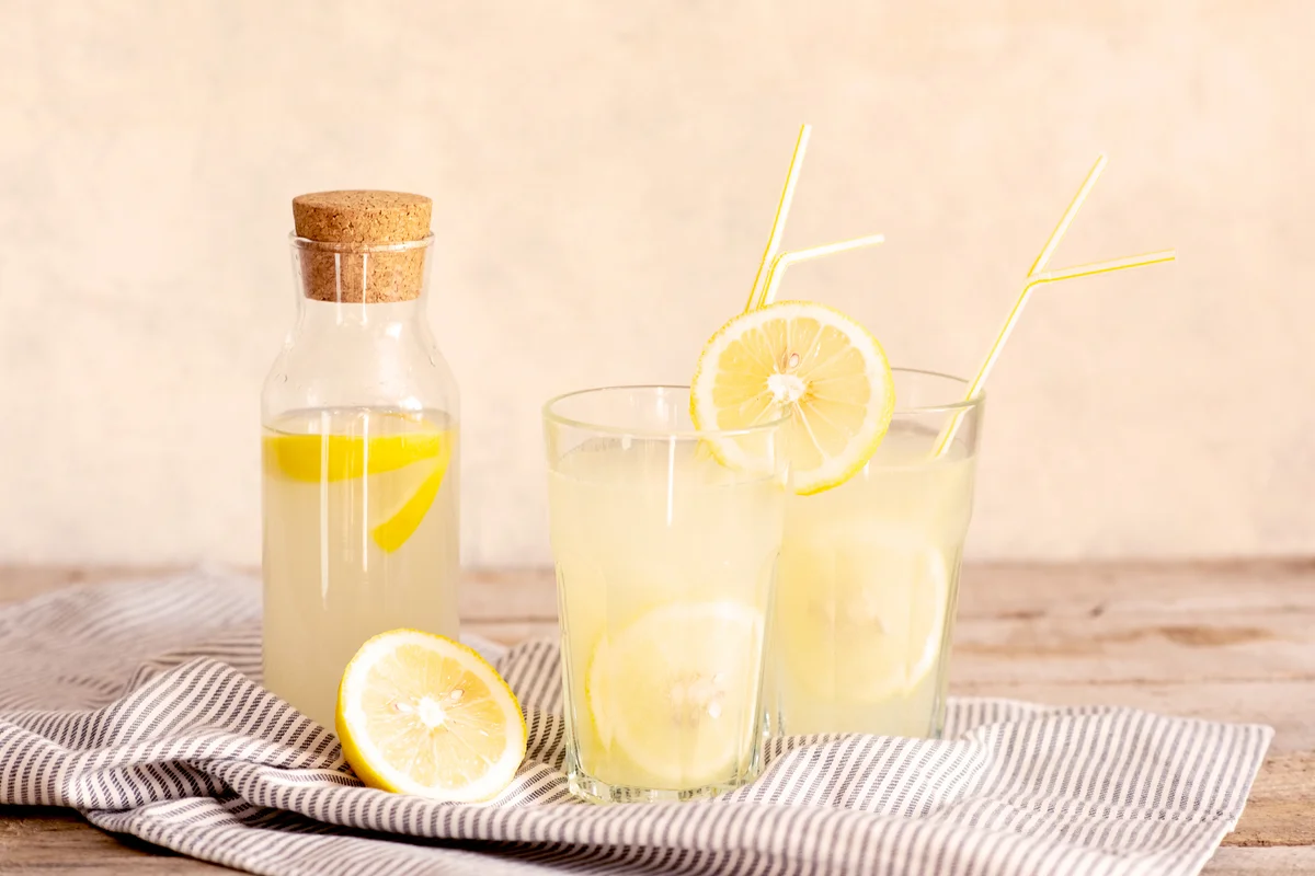 Jar of tasty fresh lemonade with lemons in background