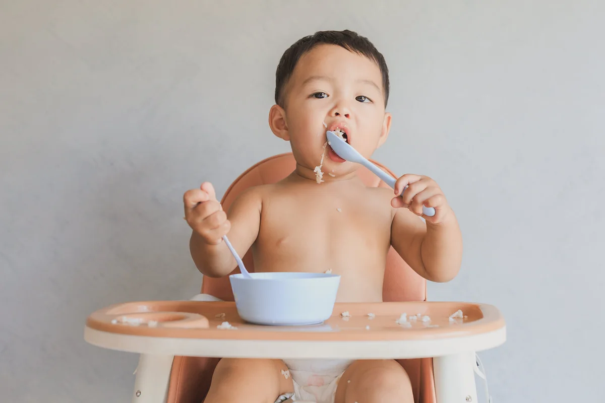 baby boy eating food by himself