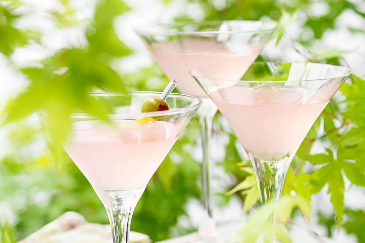 Three glasses of pink grapefruit and martini cocktails with green olives