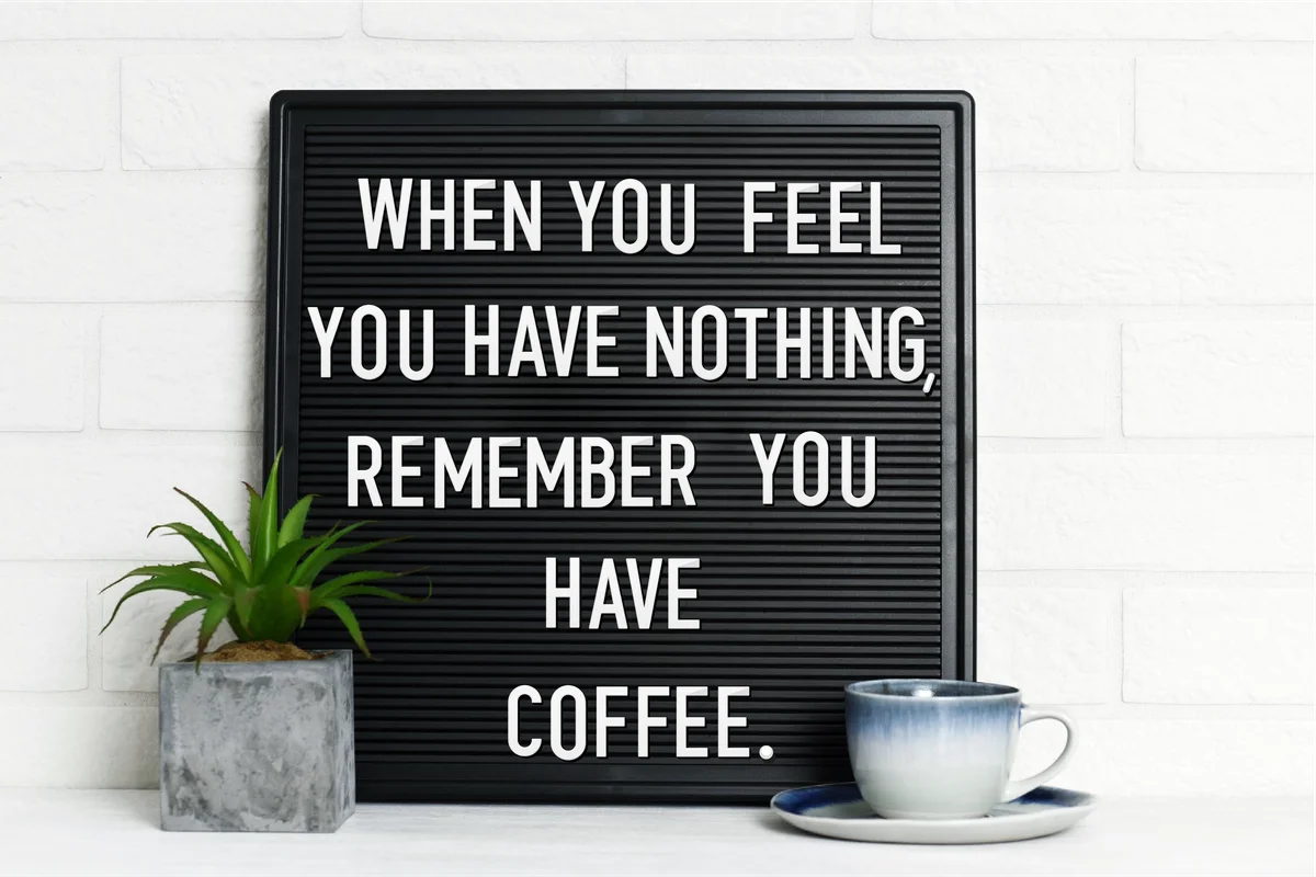 Letter board with cup of coffee and houseplant