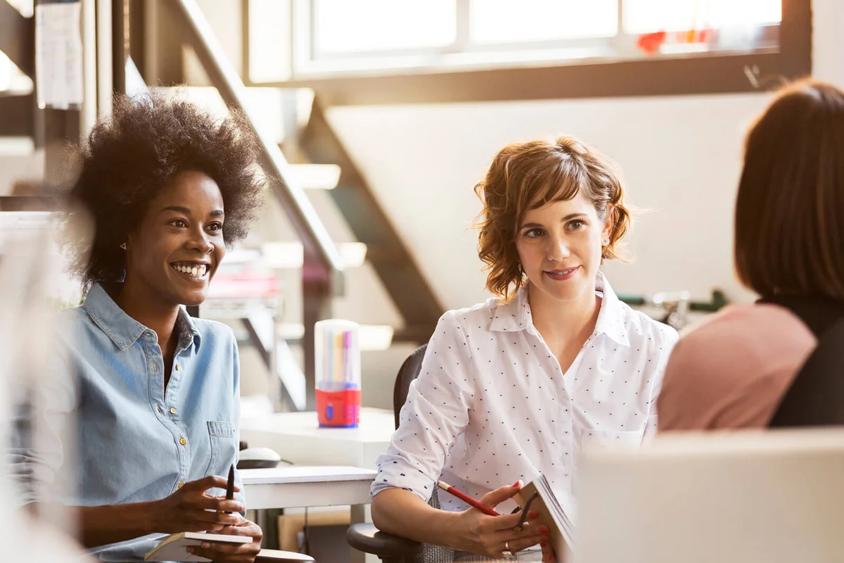 Happy businesswomen discussing with female colleague in office