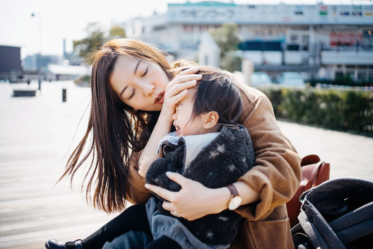 Young mother holding crying little daughter on lap