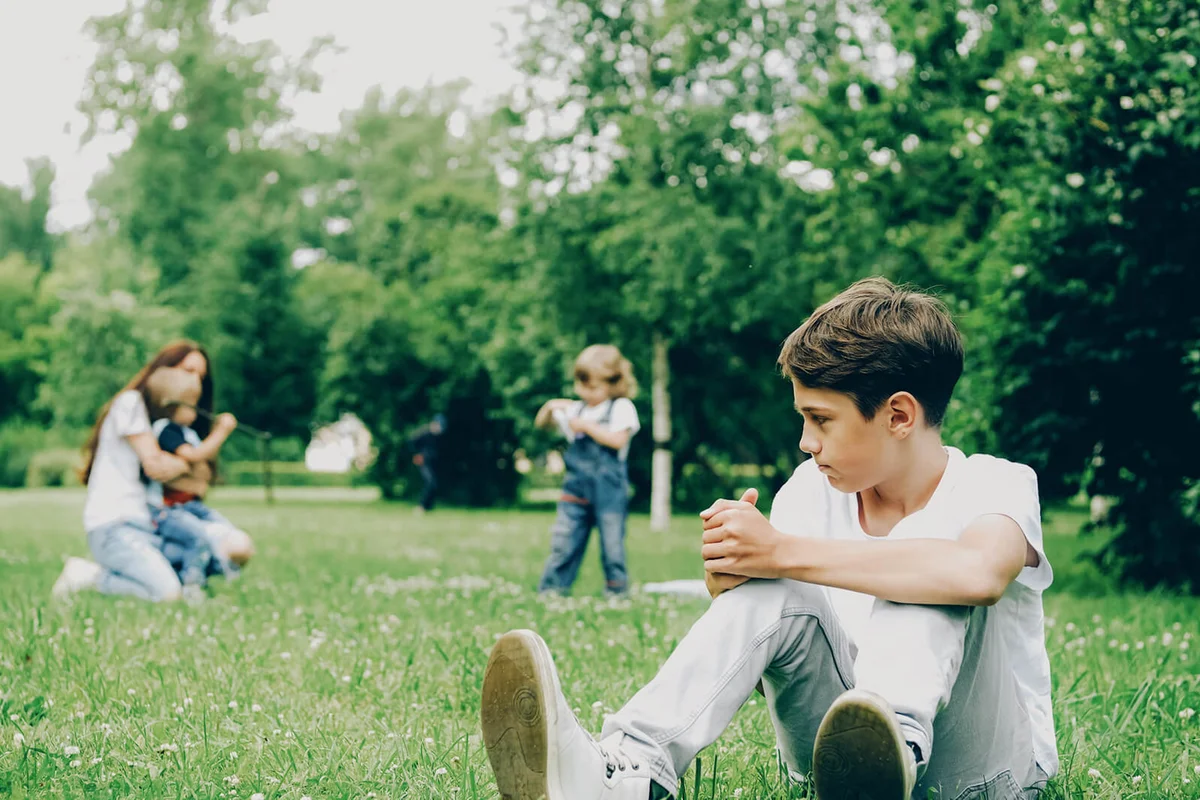 boy being sad and jealous with his mother and younger siblings