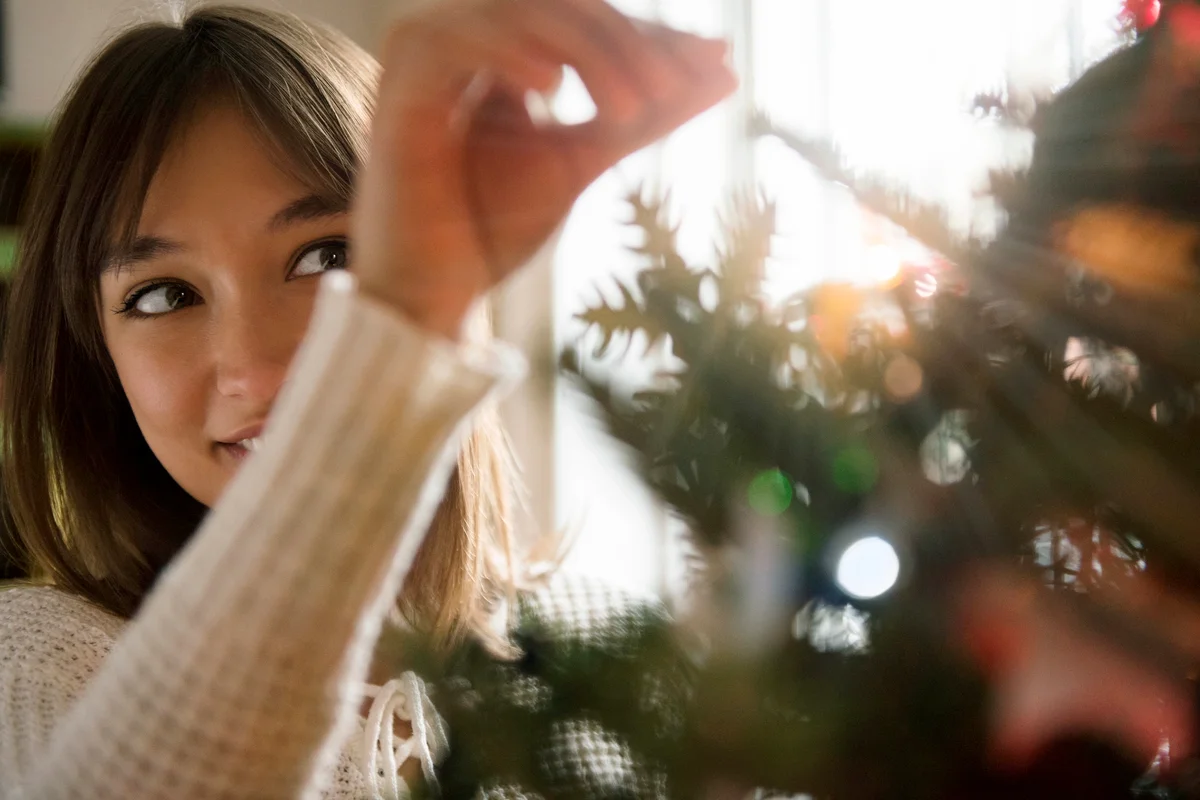 Woman placing tinsel on Christmas tree